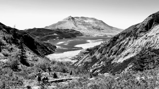A scenic view of a traveler exploring a vast natural landscape with mountains and water.