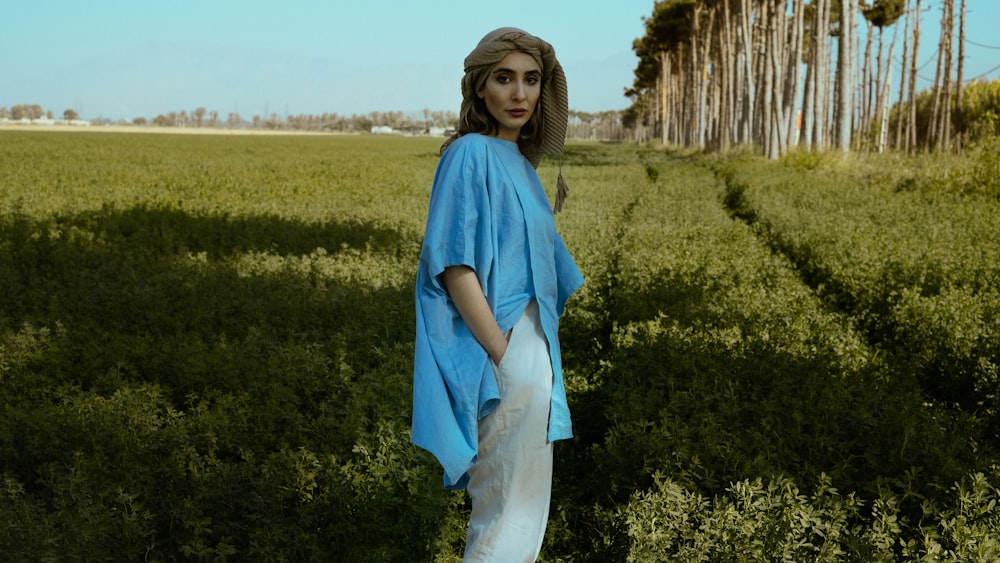 a person in a blue dress standing in a field of plants