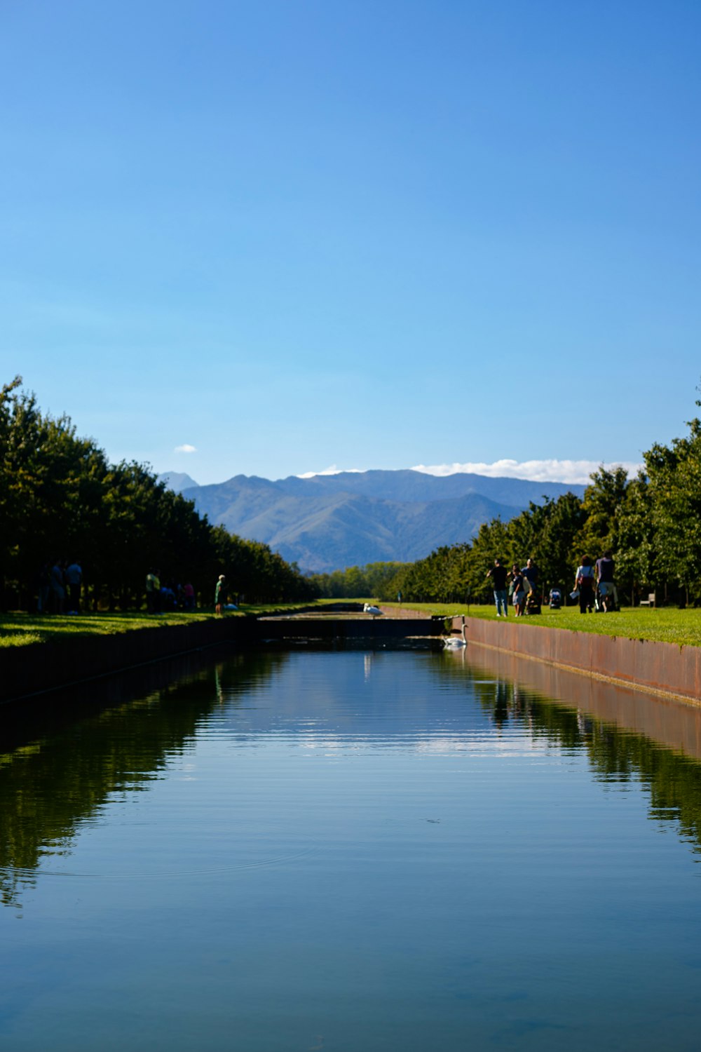 a body of water with people standing on the side of it