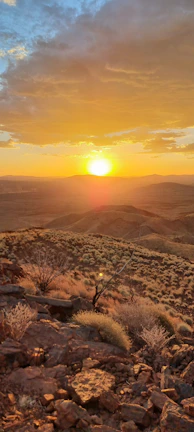A vibrant landscape photograph showcasing a sunset over rolling hills in a 3:2 ratio.
