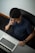 A person sitting at a desk, analyzing website analytics on a laptop with a focused expression.