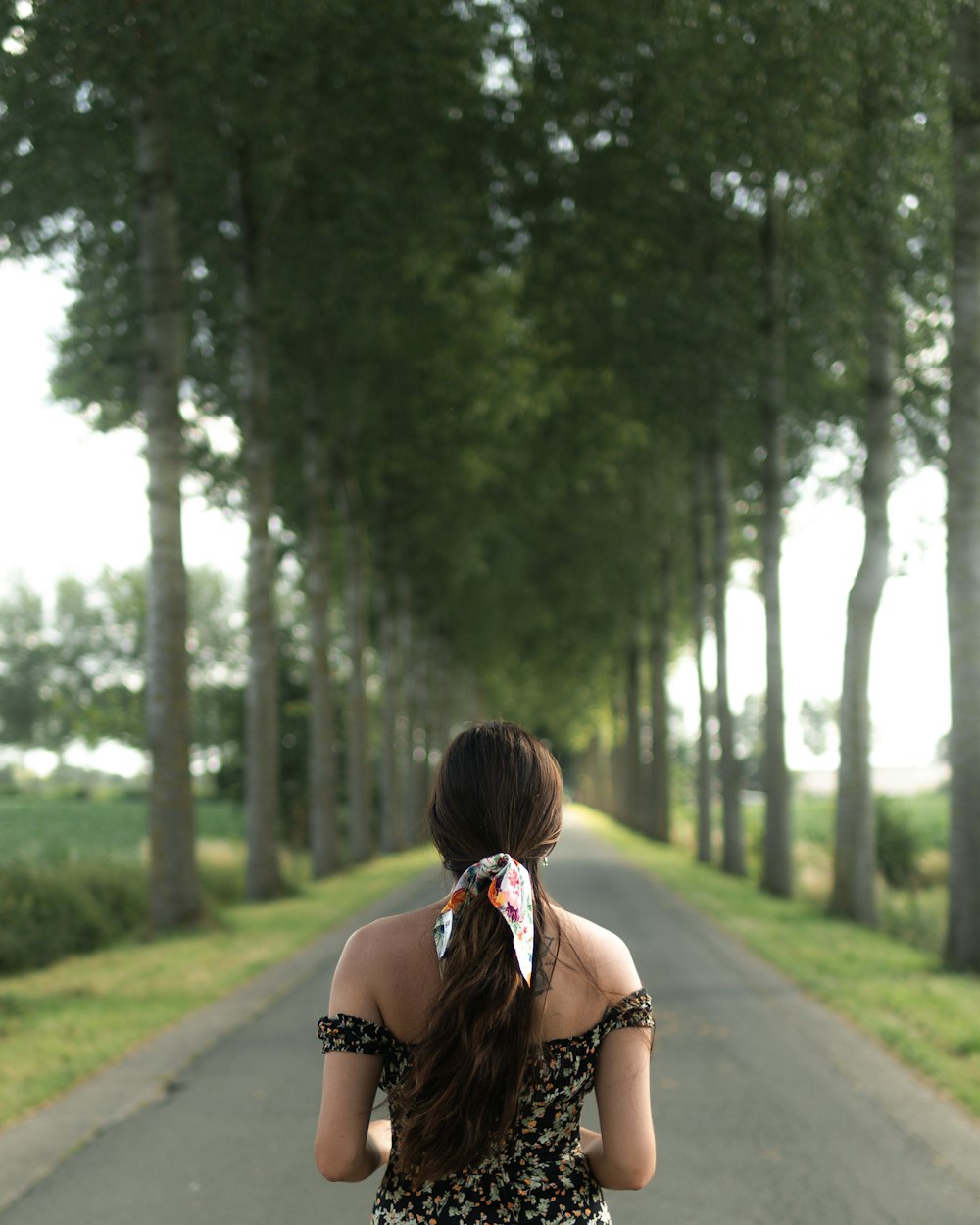 a woman with her hair in her hair walking down a path in the woods