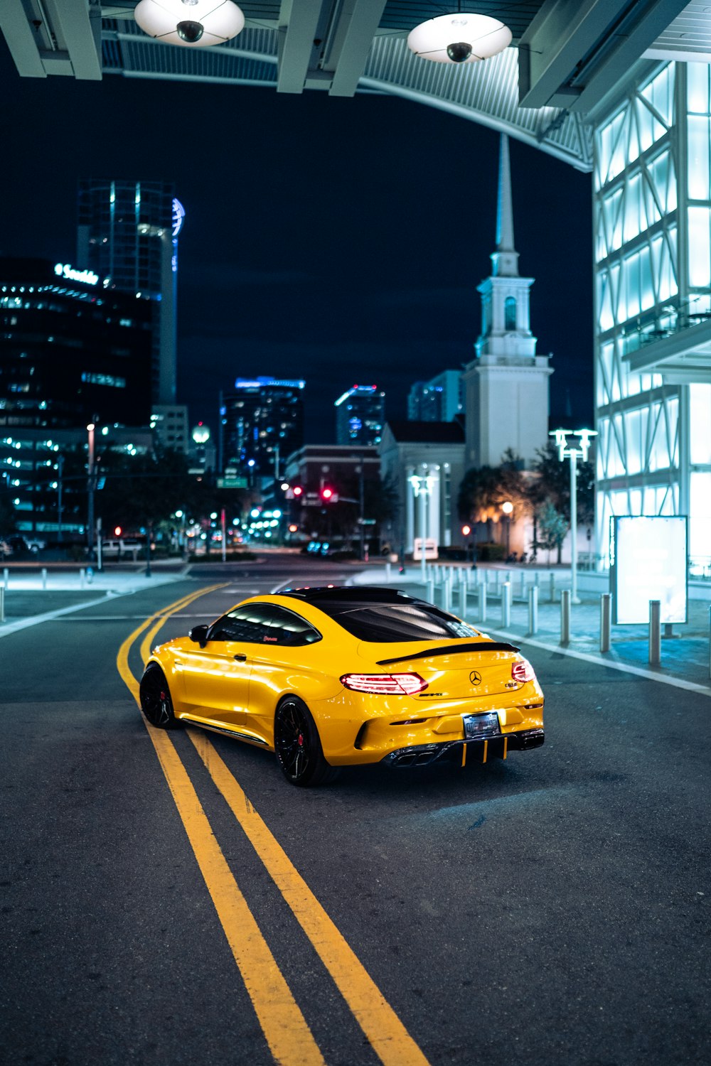 a yellow sports car on a road with buildings in the background
