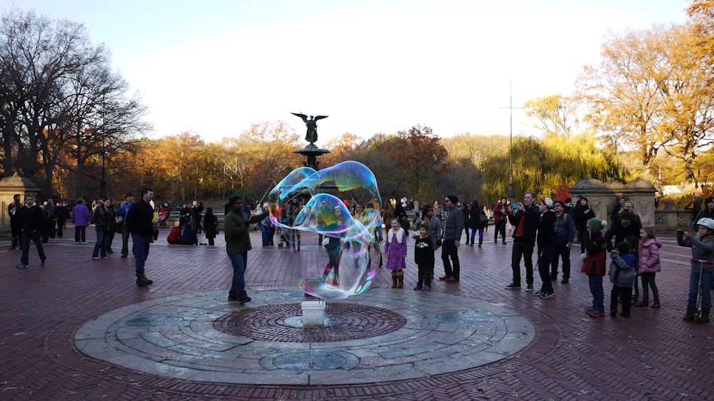 a group of people standing around a statue in a park