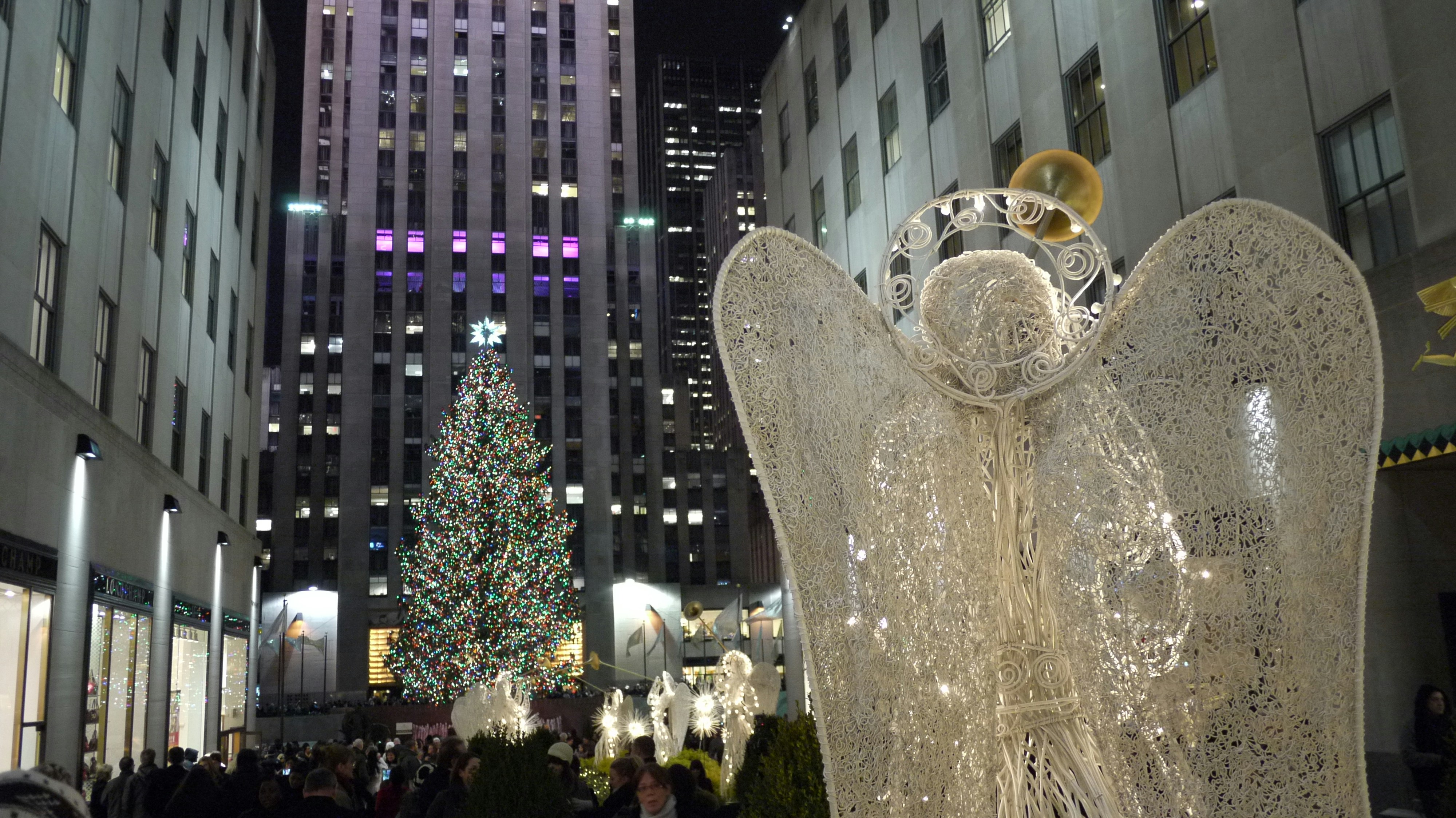 a large statue of a tree with lights and a large crowd of people, christmas, rocketeller center, new york