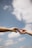 Two hands reaching towards each other against a backdrop of a clear blue sky with scattered clouds, conveying a sense of connection and intimacy.