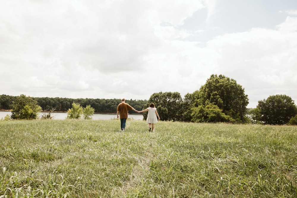 a man and woman holding hands in a field of grass