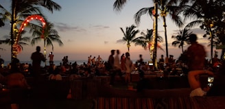 a group of people sitting on a beach at sunset