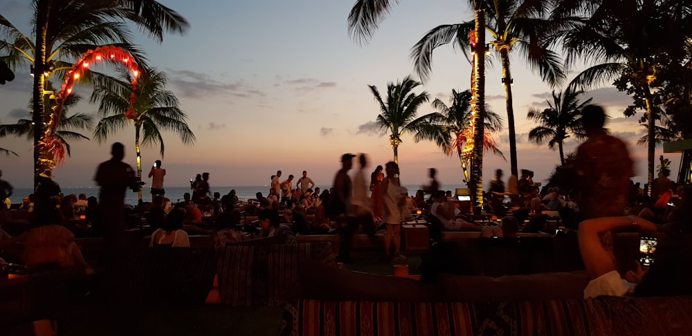 a group of people sitting on a beach at sunset