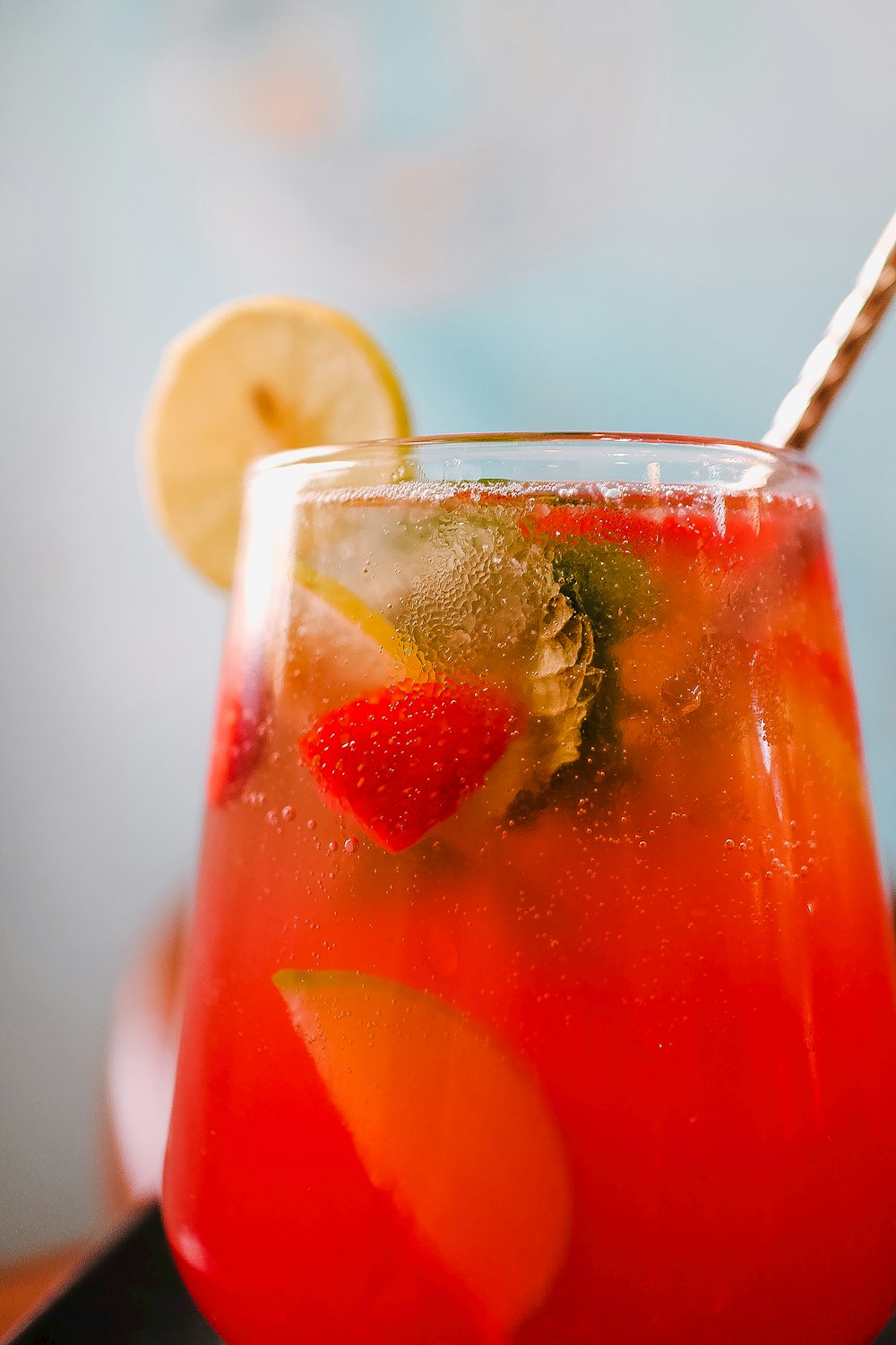 a glass of red liquid with a lemon wedge on top