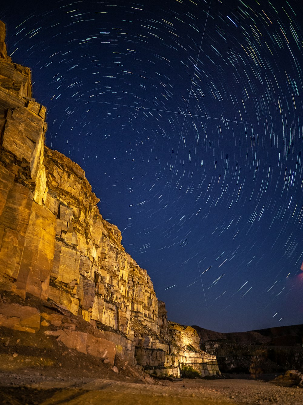 a large rock cliff with a starry sky above