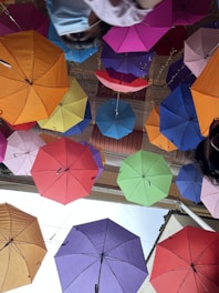 Bright patterned umbrellas hanging from a market stall on a sunny day.