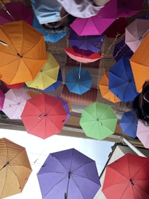 Bright patterned umbrellas hanging from a market stall on a sunny day.