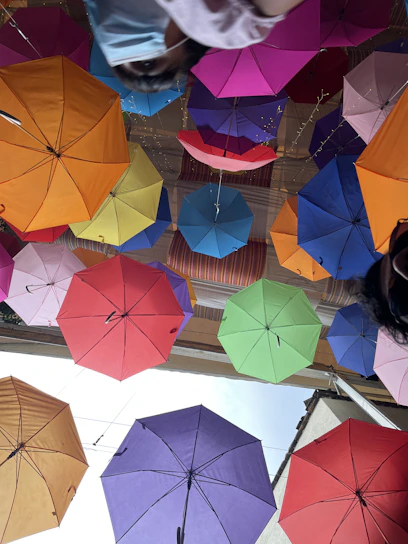 A vibrant display of colorful umbrellas hanging from above in a bright outdoor market setting.