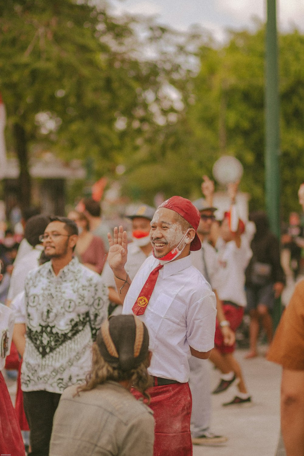 a person in a mask and tie holding the hands up