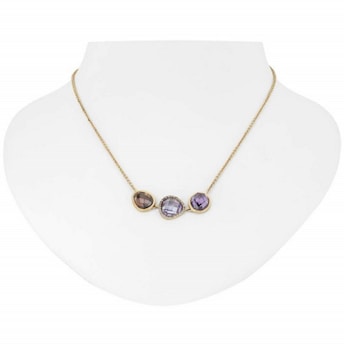 A gold necklace with three distinct gemstone pendants displayed on a white bust. The pendants include a brown, a clear, and a purple gemstone, each encased in a gold setting.