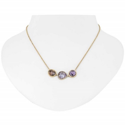 A gold necklace with three distinct gemstone pendants displayed on a white bust. The pendants include a brown, a clear, and a purple gemstone, each encased in a gold setting.