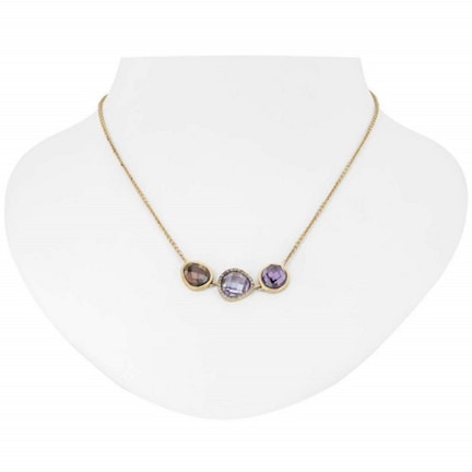 A gold necklace with three distinct gemstone pendants displayed on a white bust. The pendants include a brown, a clear, and a purple gemstone, each encased in a gold setting.
