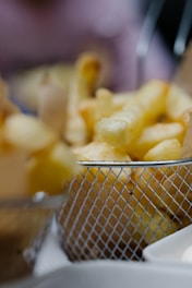 Close-up of a professional fryer basket with golden crispy fries.