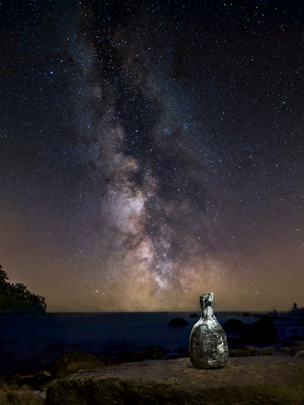 a bottle of water with a starry sky above it