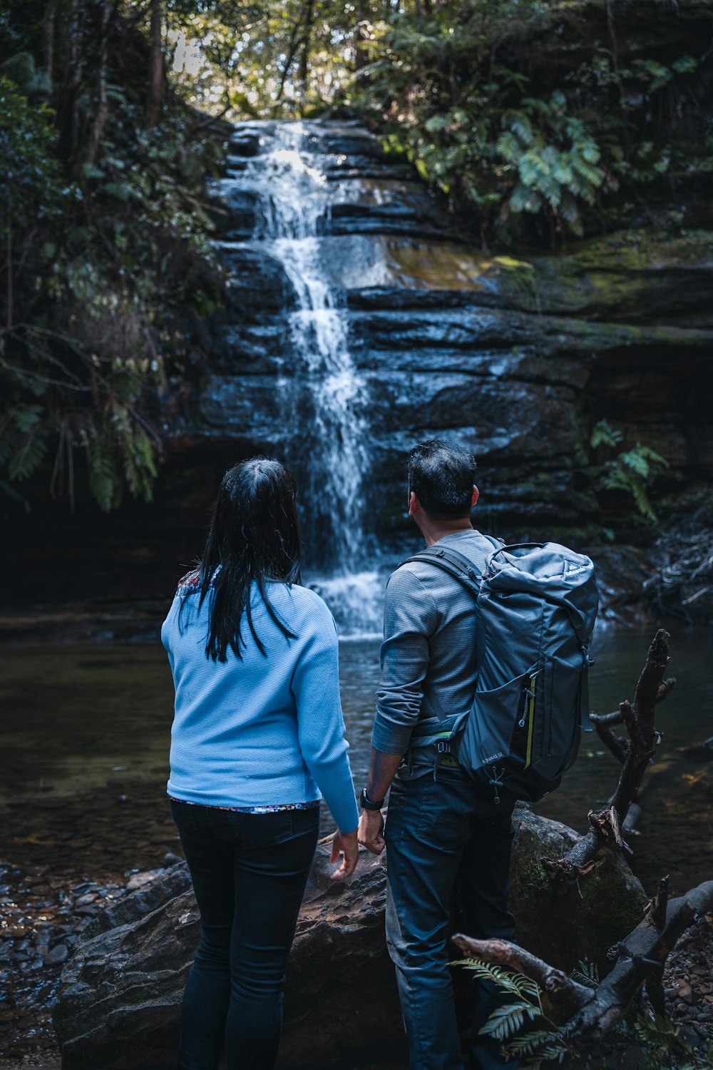 um homem e uma mulher olhando para uma cachoeira