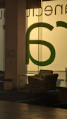Warm sitting area with a plush armchair and forest green accents near a large window.