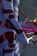 A futuristic scene featuring a humanoid figure with metallic armor-like pieces interspersed on a blue body. The setting includes abstract, twisting shapes and a glossy surface, with a mix of dark and vibrant colors creating an otherworldly appearance.