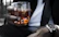 Close-up of a hand holding a glass of amber whisky with Norfolk countryside visible through a window.