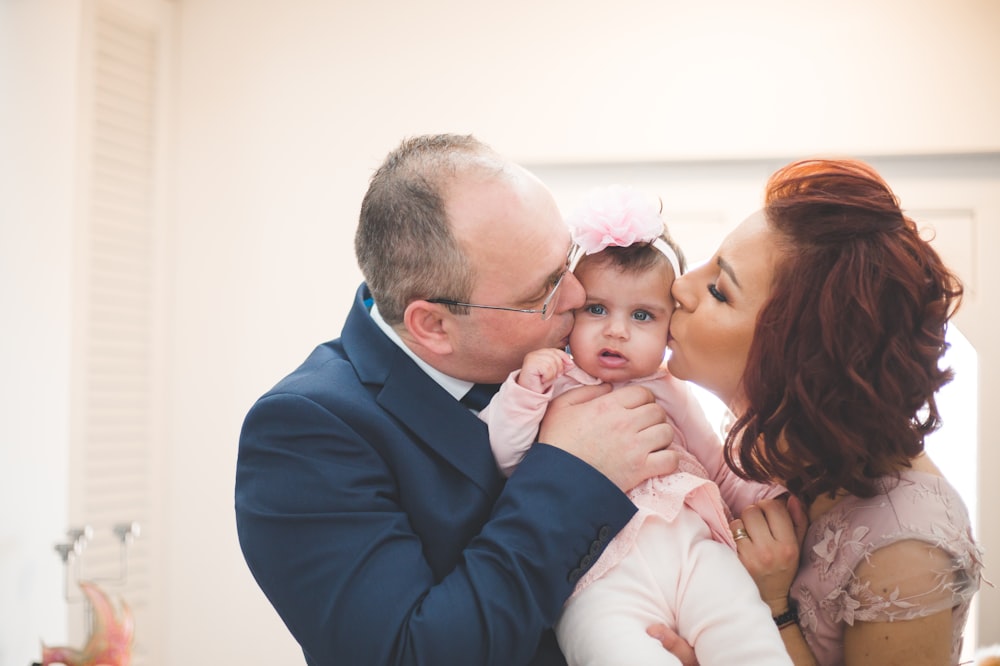 a man and woman kissing a baby