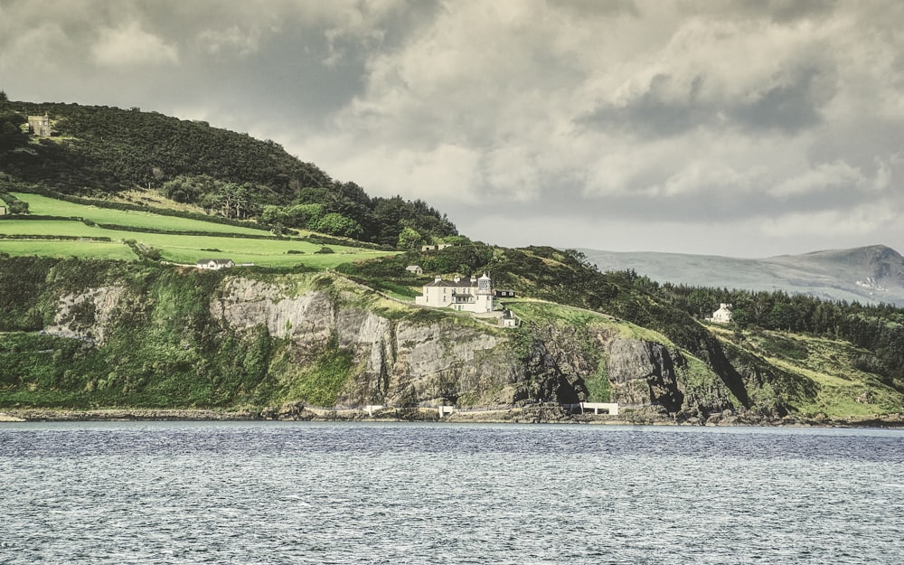 a body of water with a building on a hill by it