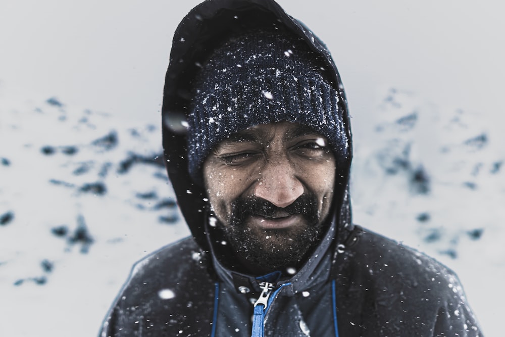 a man wearing a black head scarf and a black jacket in the snow