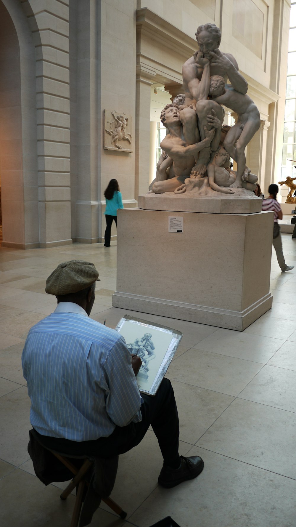 a man sitting in a chair reading a book in front of a statue