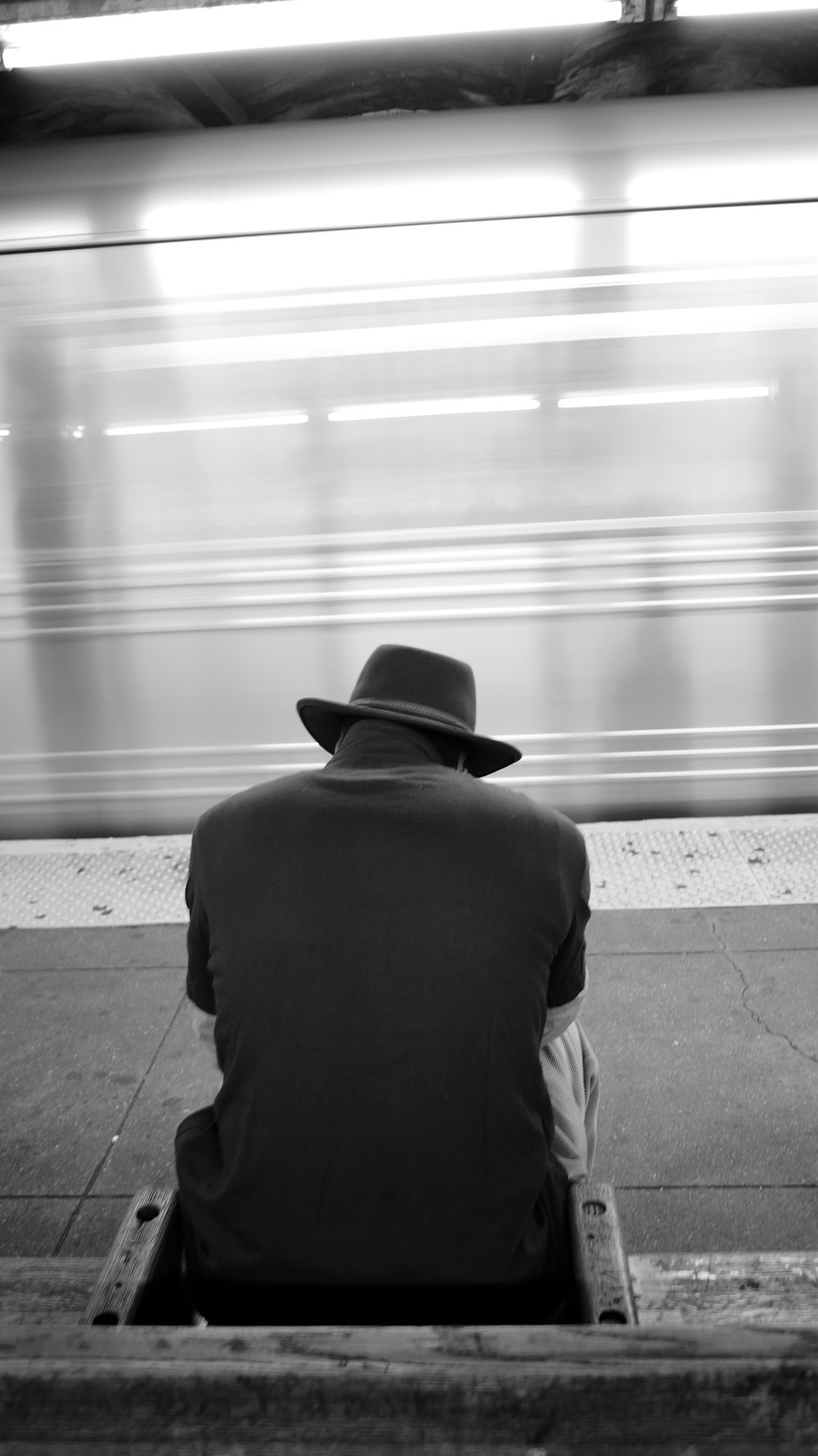 a person sitting on a bench looking at a train