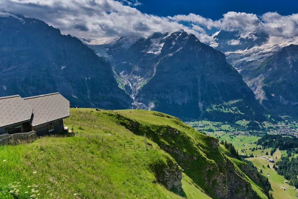 a house on a grassy hill with mountains in the background