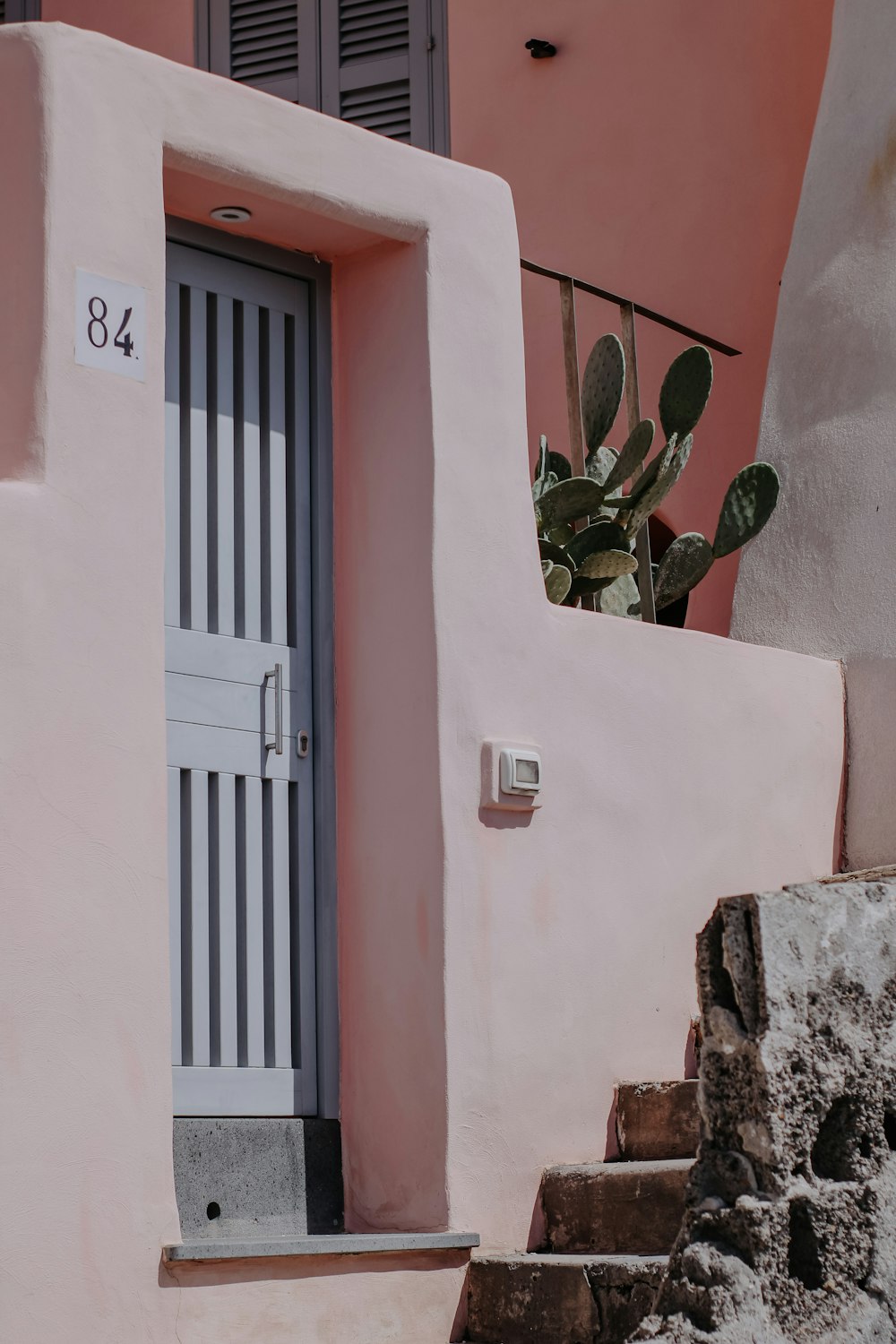 a pink building with a plant on the door