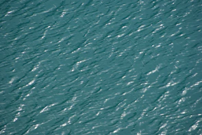 Close-up of gentle water ripples reflecting sunlight, evoking fluid motion.