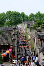 A lively street scene in a historic Chinese town with colorful lanterns and smiling locals sharing traditional crafts.