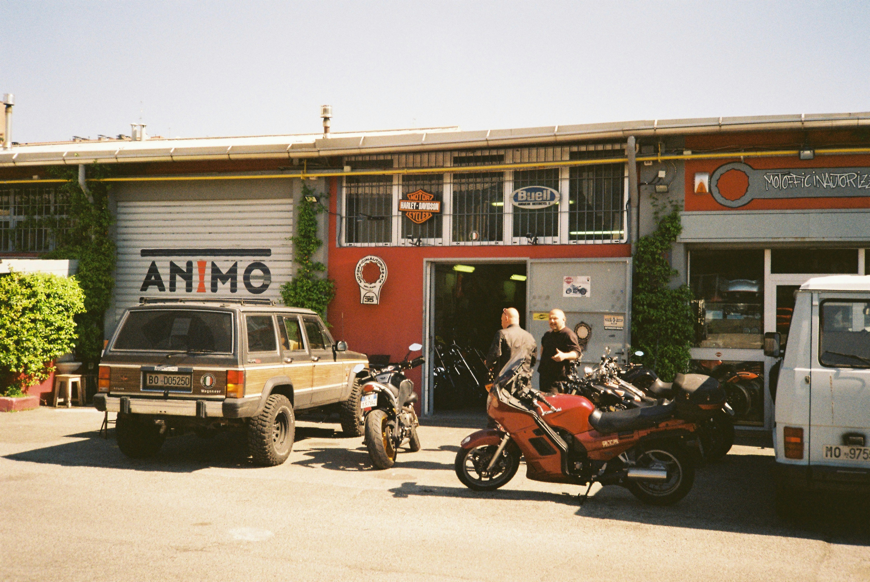 a couple of men standing next to motorcycles in front of a store