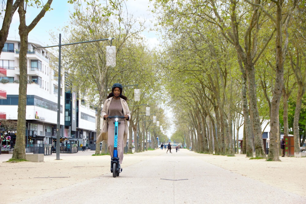 a person riding a bicycle on a street with trees on the side