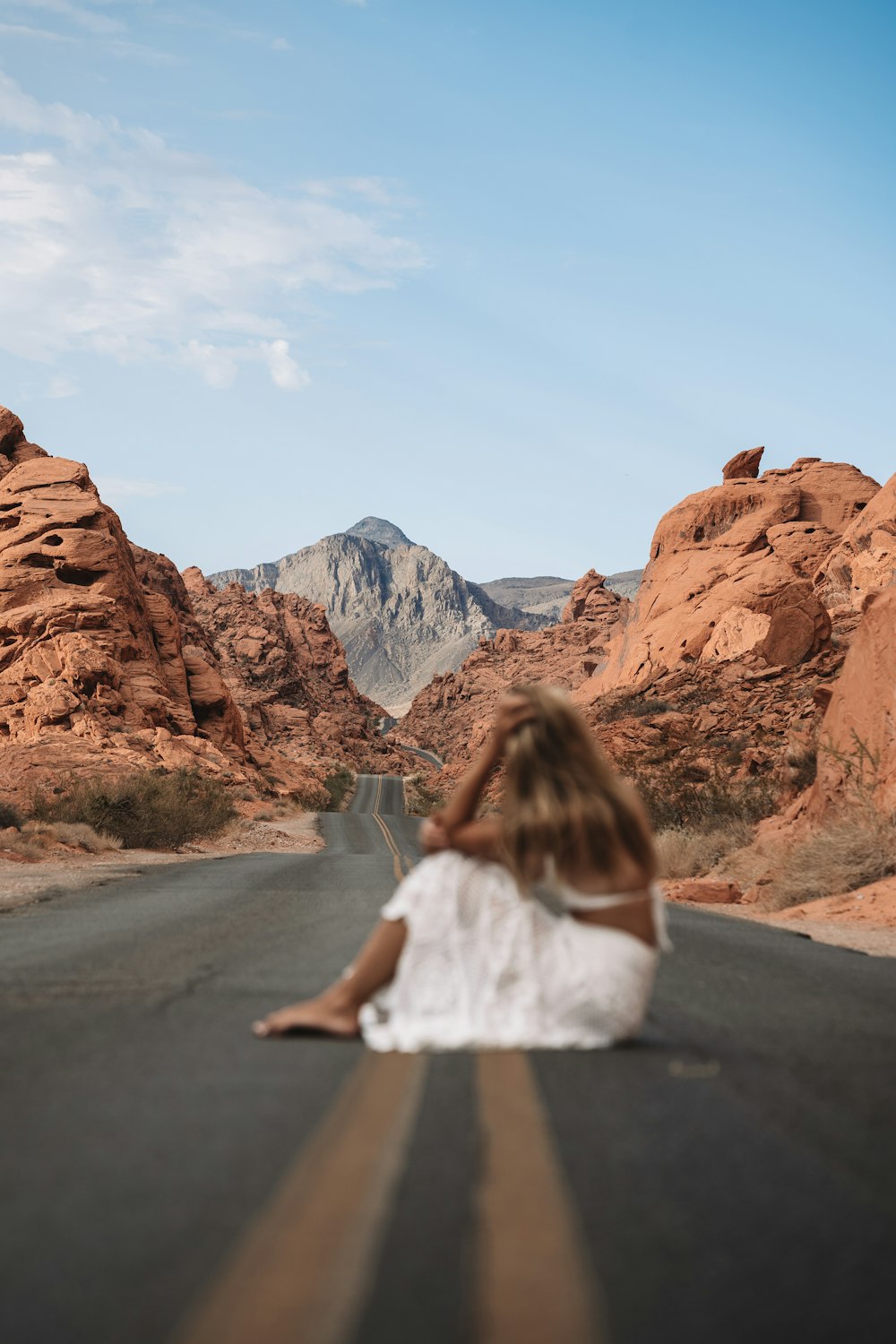 a man sitting on a road looking at a mountain range