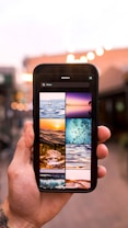A hand holding a smartphone with its screen displaying a search for 'Water', showing various images of water-related themes such as droplets, ocean waves, and underwater scenes. The background is blurred, suggesting a cityscape with lights.