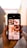 A hand is holding a smartphone displaying images related to newborns. The screen shows a grid of photos, including close-ups of baby feet, a baby wrapped in a blanket, and a baby being held by an adult. The background appears to be an alleyway with blurred walls and a light source visible.
