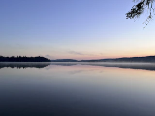 Horizontal wide-angle shot of a misty lake at dawn with gentle ripples.