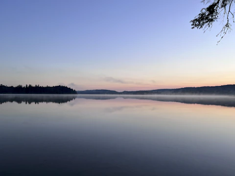 Horizontal wide-angle shot of a misty lake at dawn with gentle ripples.
