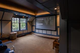 Wide shot of a privateflix theatre room showing the HD screen, surround sound speakers, and intimate seating.