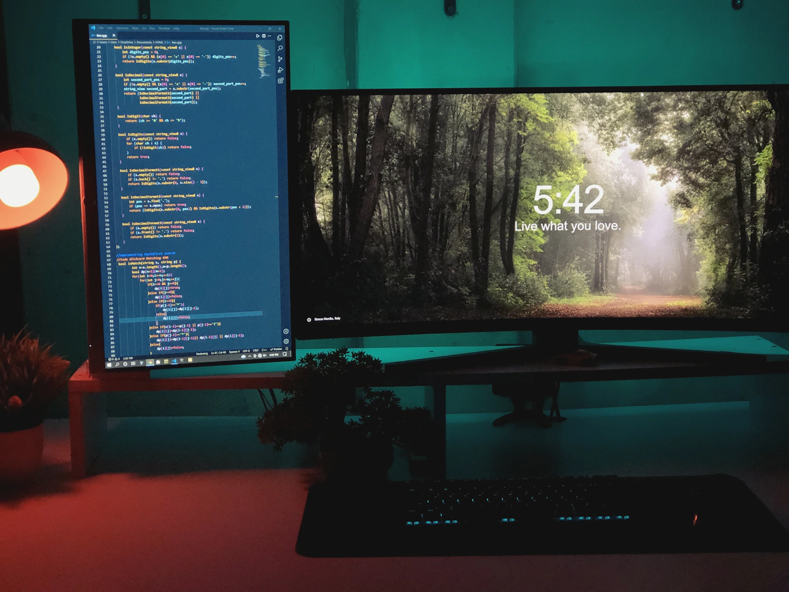 A warm coding workspace with monitors, plants, and forest imagery
