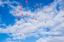 Close-up of a single red heart-shaped balloon floating against a clear blue sky.