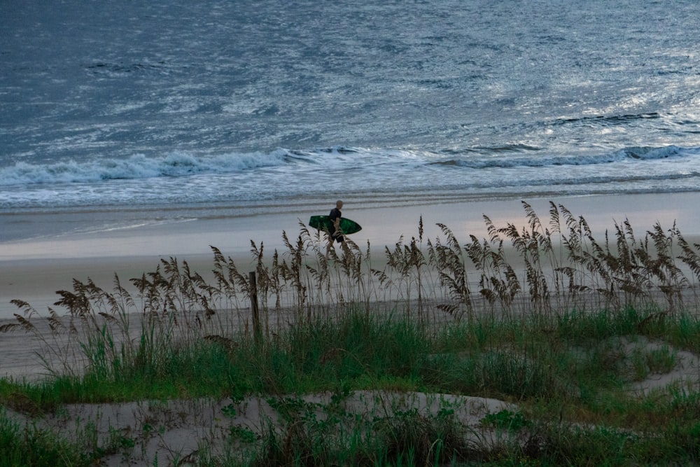 a person carrying a surfboard on a beach