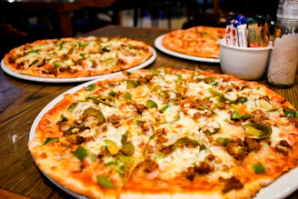 Three pizzas arranged on a wooden table showcasing the promo deal.