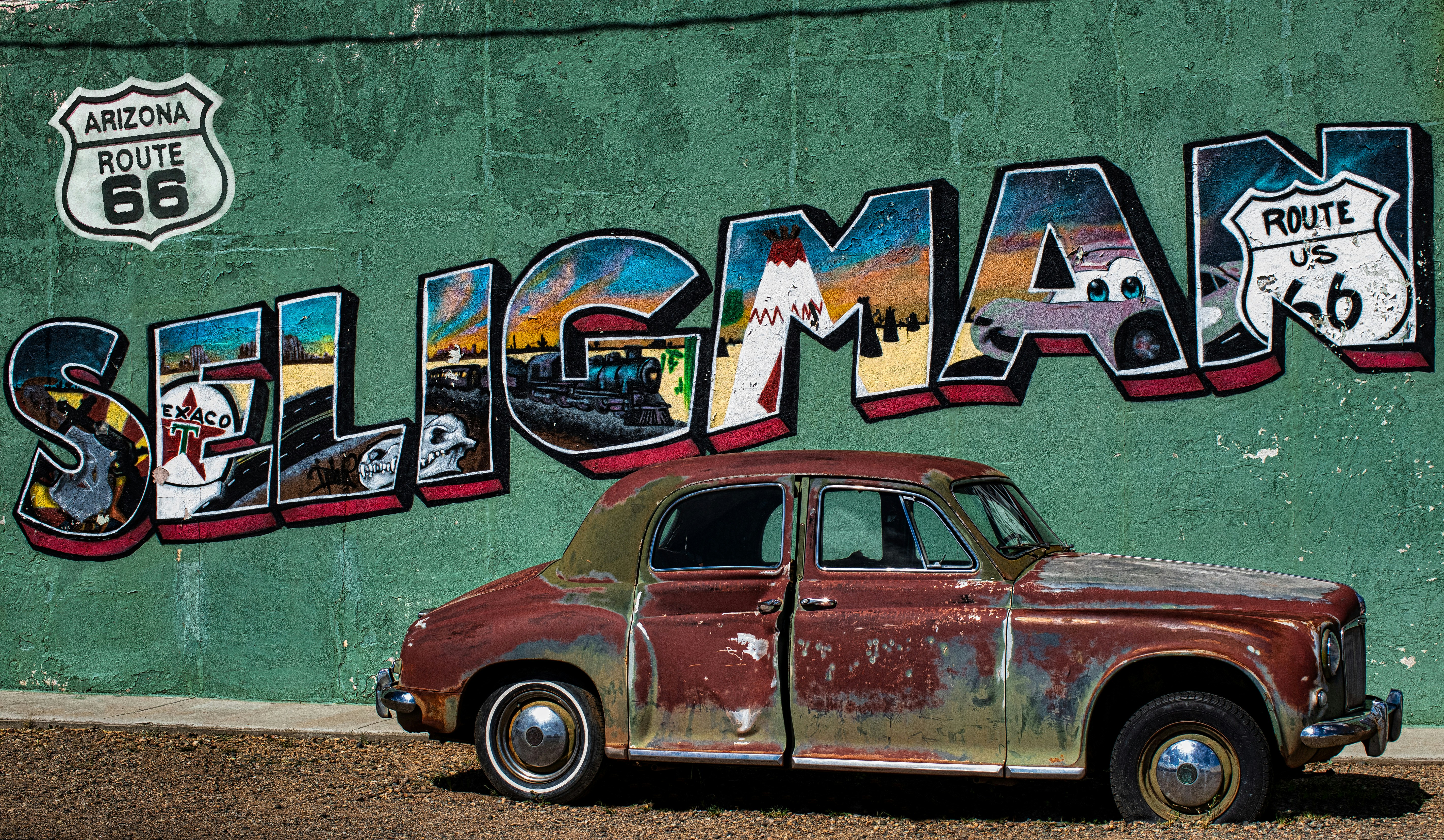 a car parked in front of a wall with art